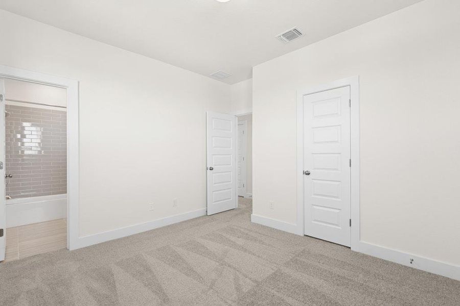 Unfurnished bedroom with carpet flooring and ensuite bath Unfurnished bedroom with carpet flooring and ensuite bath