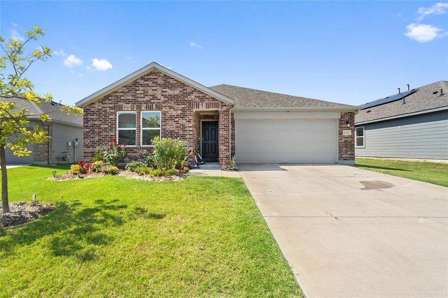 Ranch-style house featuring brick siding, an attached garage, driveway, and a front yard