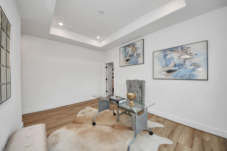 This bright and elegant office space features a sleek glass desk, warm wood flooring, and modern art, creating a perfect blend of style and functionality for inspired productivity.