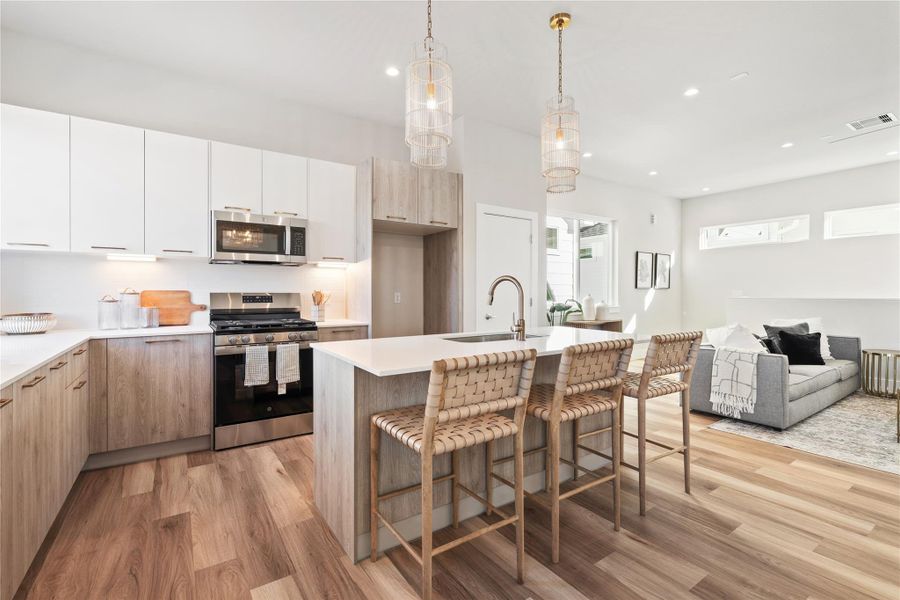 Two toned, European style cabinetry wraps the kitchen, balancing warm wood tones with crisp, modern lines.