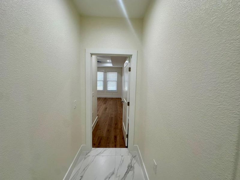 Hall with light marble finish floors and a textured wall
