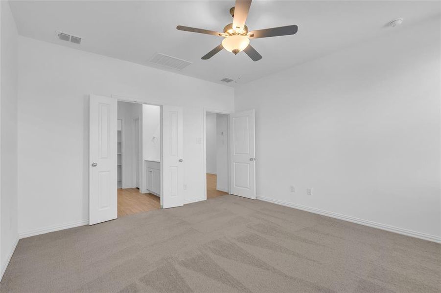 Unfurnished bedroom featuring ceiling fan, light colored carpet, and ensuite bathroom