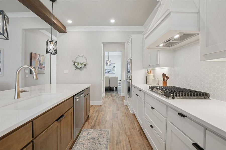 Kitchen with crown molding, light wood-look ceramic tile floors, light countertops, recessed lighting, and white cabinets