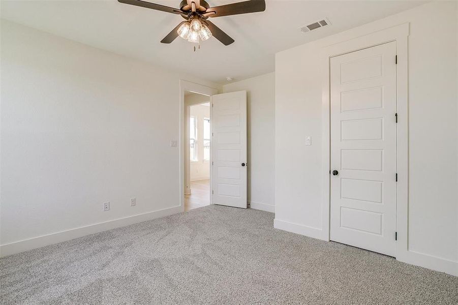 Unfurnished bedroom featuring ceiling fan and light colored carpet