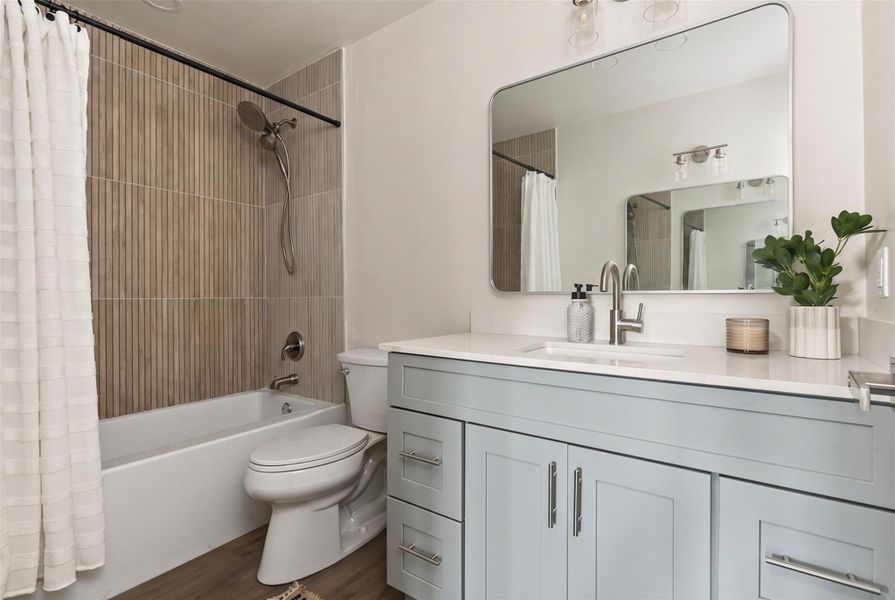 A well-lit bathroom features a vanity with a sleek sink and a shower-tub combination.
