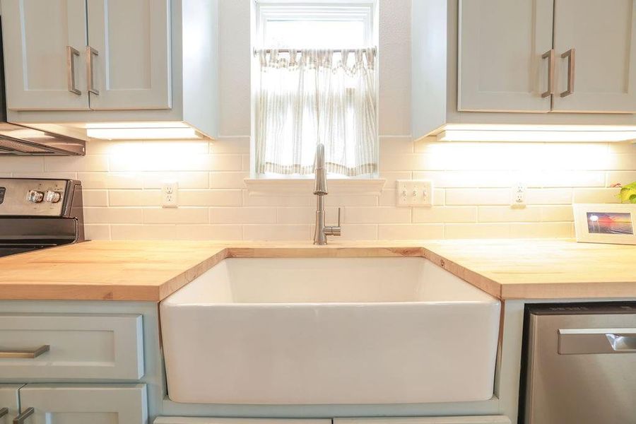 Kitchen featuring wooden counters, stainless steel dishwasher, electric range oven, and tasteful backsplash