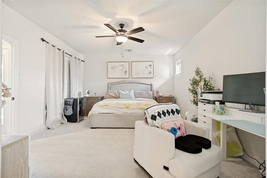 Carpeted bedroom featuring a ceiling fan with integrated lighting, a window with blinds, and white walls