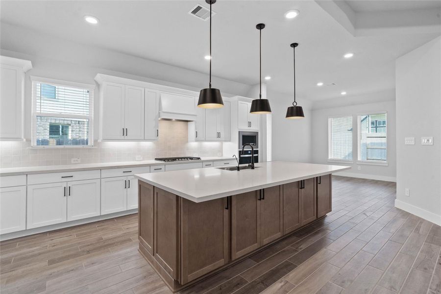 The stunning and generously sized center island features a breakfast bar, perfect for casual dining and entertaining. The island is beautifully designed with pristine quartz countertop and modern pendant lights.