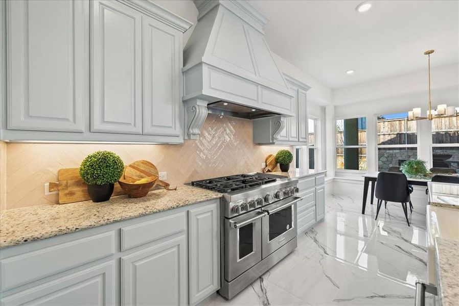 Kitchen with custom cabinetry, 6-burner gas range, double oven, quartz countertops, decorative light fixtures, and light marble flooring Kitchen with custom cabinetry, 6-burner gas range, double oven, quartz countertops, decorative light fixtures, and light marble flooring