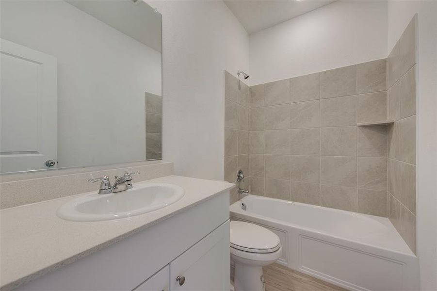 Full bathroom with wood-type flooring, tiled shower / bath, vanity, and toilet