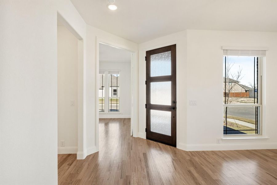 Entryway with dark wood glass-panel front door, hardwood floors, and white walls