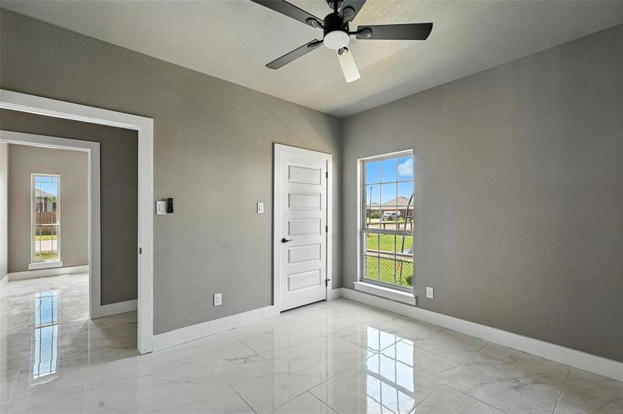 Spare room featuring light marble finish floors and a ceiling fan Spare room featuring light marble finish floors and a ceiling fan