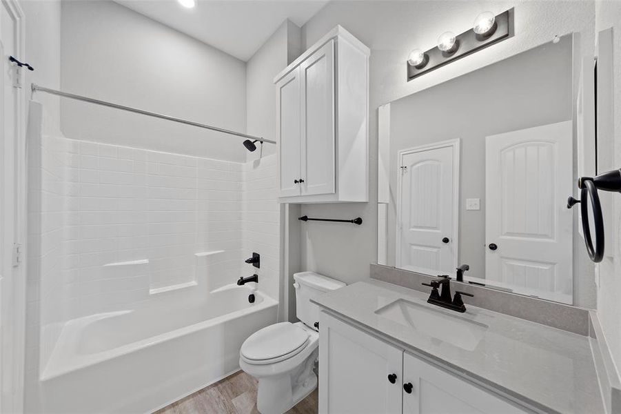 Full bathroom with vanity, hardwood / wood-style floors, shower / bathing tub combination, and toilet