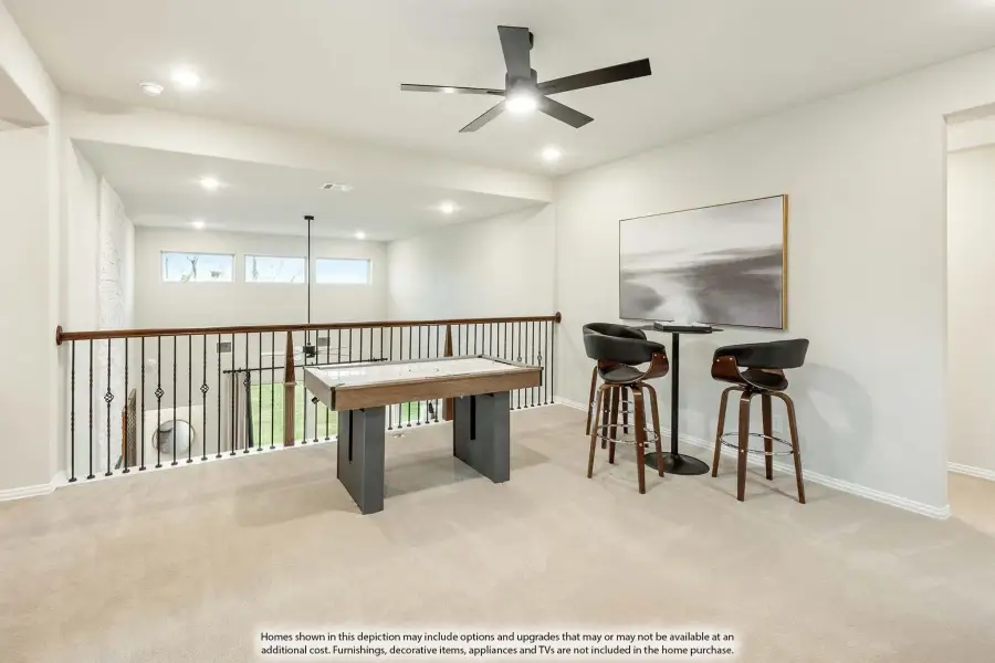 Upstairs loft with air hockey table, bar seating, ceiling fan, and iron railing overlooking lower level