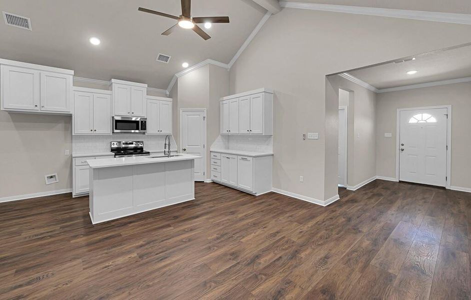 Kitchen with stainless steel appliances, a ceiling fan, light countertops, decorative backsplash, and white cabinetry