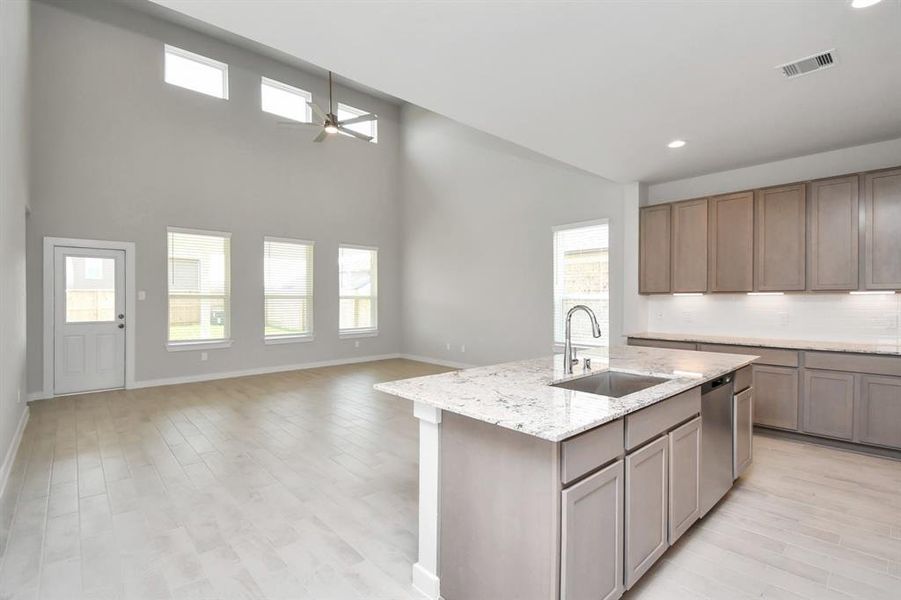 Culinary haven, featuring granite countertops, a tile backsplash, stainless steel appliances, 42” upper cabinets, and undercabinet lighting. Sample photo of completed home with similar floor plan. As-built interior colors and selections may vary.