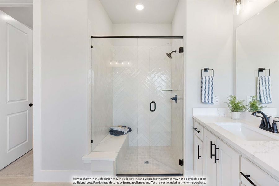 Bathroom with glass walk-in shower, herringbone tile, built-in bench, and white vanity with dark hardware