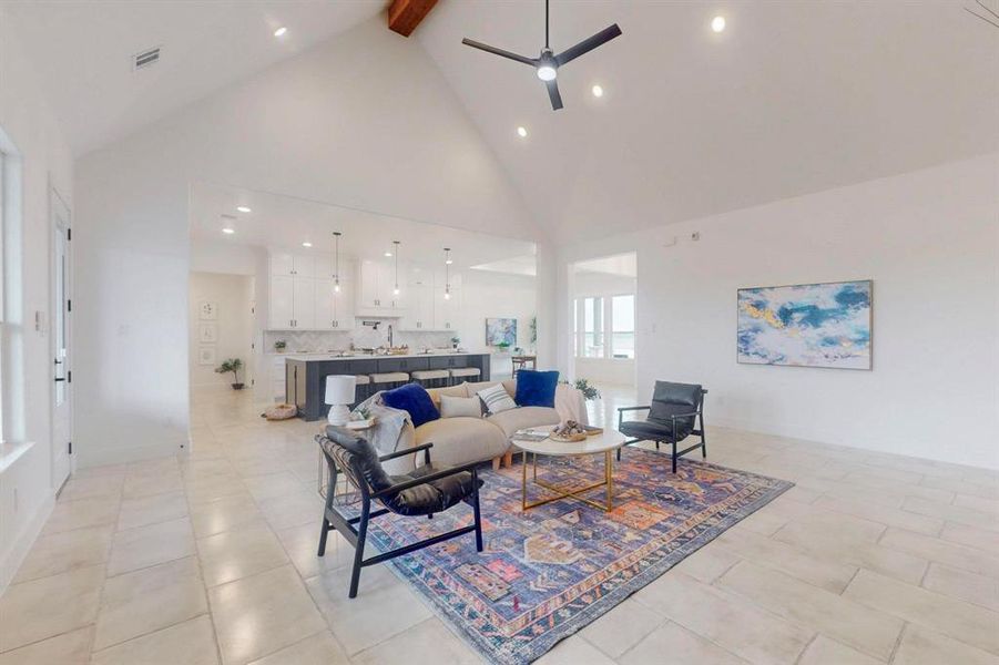 Living area featuring light tile patterned flooring, high vaulted ceiling, visible vents, beamed ceiling, and a ceiling fan Living area featuring light tile patterned flooring, high vaulted ceiling, visible vents, beamed ceiling, and a ceiling fan
