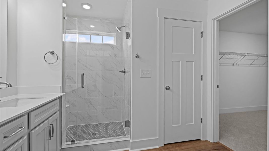 Memorable mornings begin in this elegant primary bathroom with tiled walk-in shower and double vanity