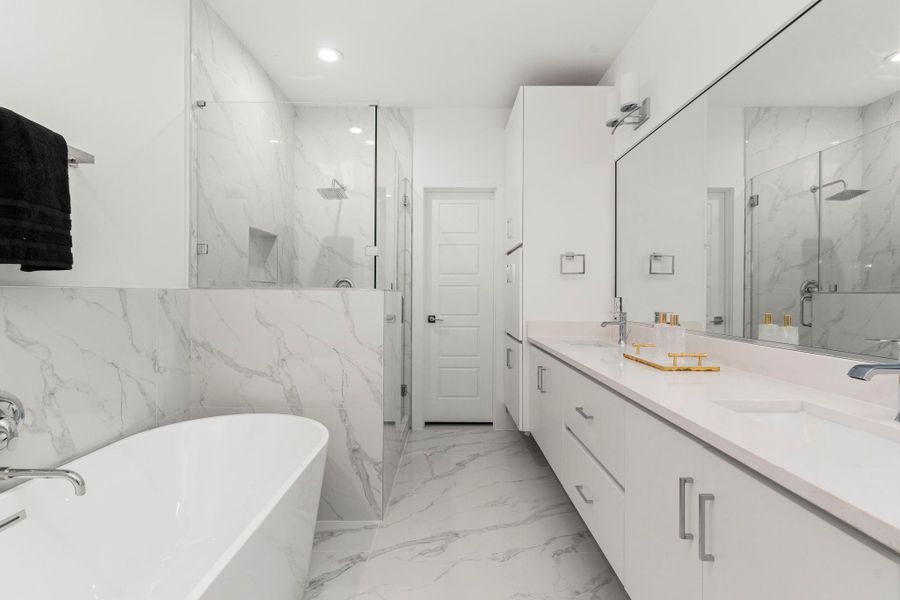 Elegant Primary Bath featuring double sinks, a spacious mirror, separate glass-enclosed shower, and a relaxing soaking tub—this-suite bath blends function with luxury.