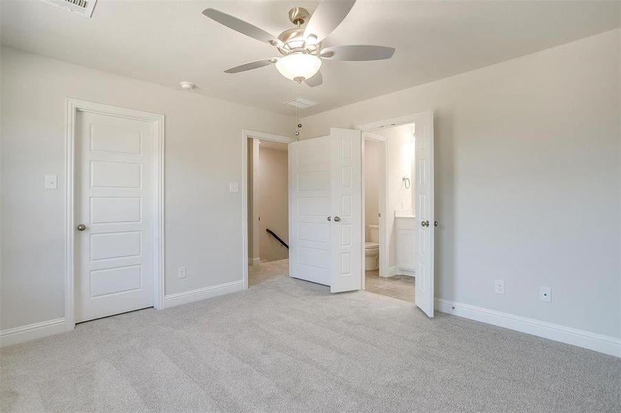 Unfurnished bedroom featuring light colored carpet, ensuite bath, and a ceiling fan Unfurnished bedroom featuring light colored carpet, ensuite bath, and a ceiling fan