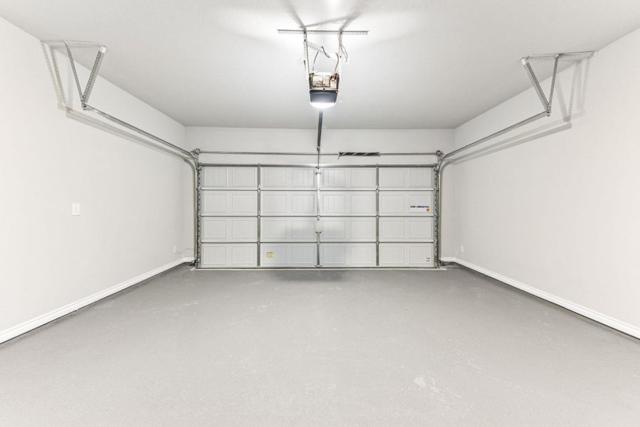 Garage with baseboards and a garage door opener Garage with baseboards and a garage door opener