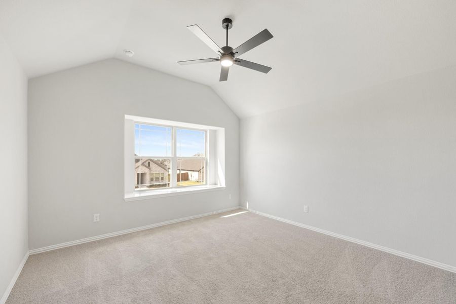 Empty bedroom with vaulted ceiling, ceiling fan, carpet flooring, and a large window with neighborhood view