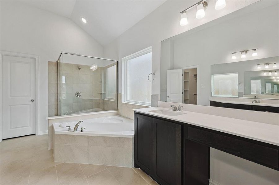 Bathroom with vanity, separate shower and tub, lofted ceiling, and tile patterned flooring