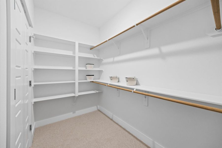 A spacious and well-organized primary walk-in closet designed for maximum storage and convenience. The closet features custom-built shelving and hanging rods to accommodate a variety of clothing and accessories. Soft, recessed lighting illuminates the space, creating a bright and inviting atmosphere A spacious and well-organized primary walk-in closet designed for maximum storage and convenience. The closet features custom-built shelving and hanging rods to accommodate a variety of clothing and accessories. Soft, recessed lighting illuminates the space, creating a bright and inviting atmosphere