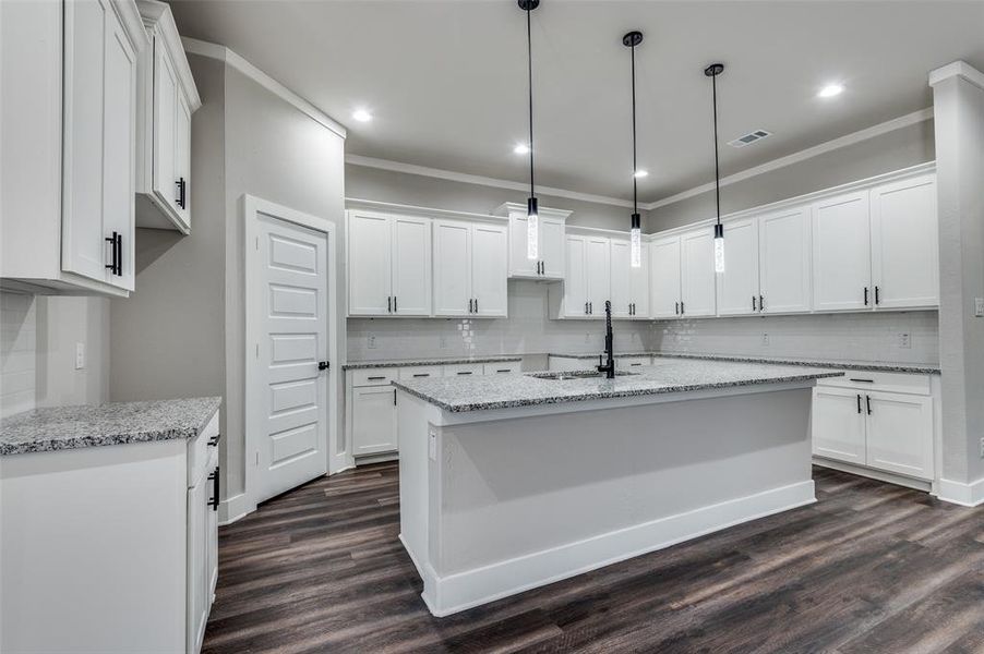 Kitchen featuring backsplash, dark wood-style floors, crown molding, recessed lighting, and a center island with sink Kitchen featuring backsplash, dark wood-style floors, crown molding, recessed lighting, and a center island with sink