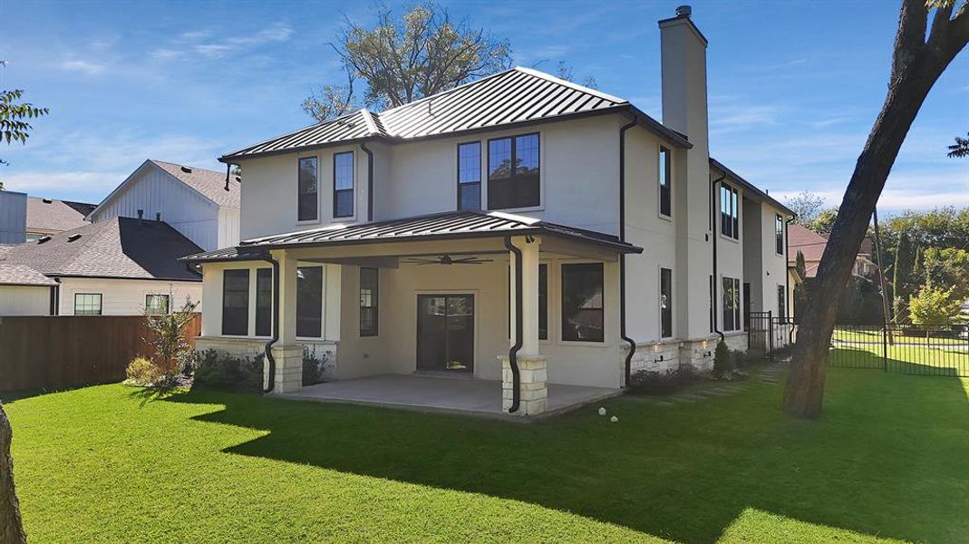 Rear view of house with a fenced backyard, a standing seam roof, and a metal roof Rear view of house with a fenced backyard, a standing seam roof, and a metal roof
