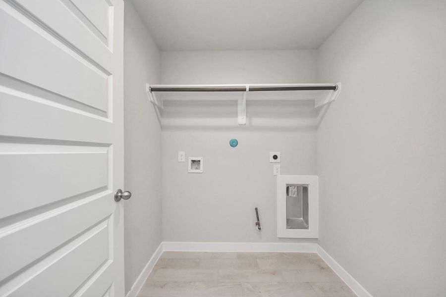 A perfect blend of functionality and comfort. Capture the essence of easy living with a first-floor laundry room, thoughtfully equipped with shelving for effortless organization. Both electric and gas connections available. Sample photo of completed home with similar floor plan. Actual colors and selections may vary.