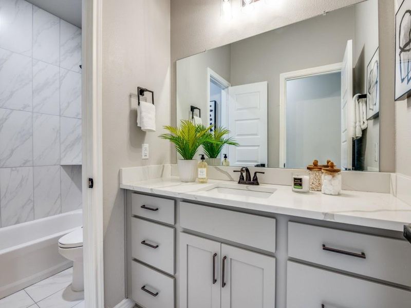Bathroom featuring toilet, vanity, marble finish floor, and washtub / shower combination Bathroom featuring toilet, vanity, marble finish floor, and washtub / shower combination
