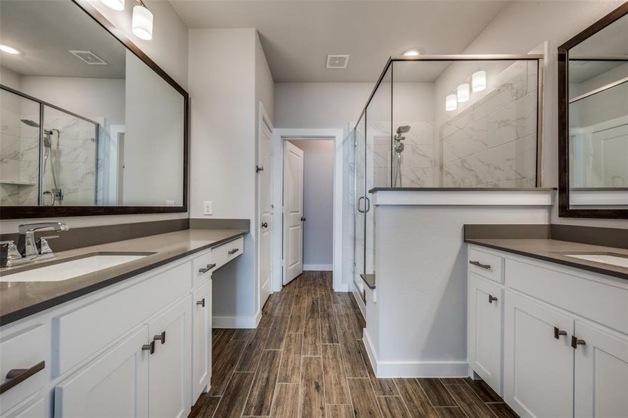 Full bath featuring a sink, visible vents, wood finish floors, and a stall shower