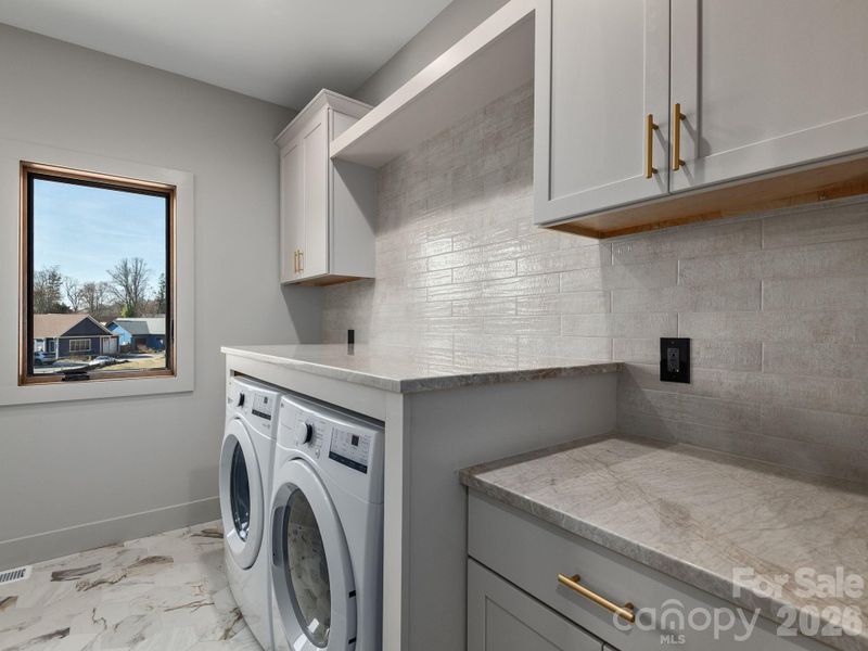 Representative photo from 50 Verde Drive showing the builder’s quality of construction and finish level, including the laundry room with GE front-load washer and electric dryer, granite countertops, large tiled backsplash, ceramic tile floors, and Wolf cabinetry.