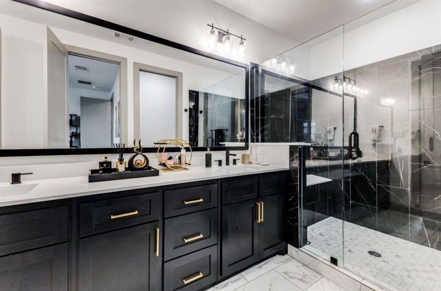 Primary Bathroom featuring double vanity, a marble finish shower, and light marble finish flooring