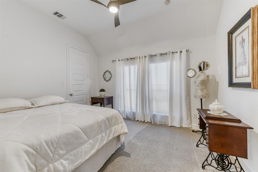 Bedroom with vaulted ceiling, carpet flooring, and a ceiling fan