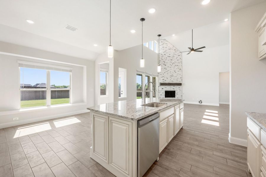 Kitchen island with granite countertop and stainless dishwasher, open to living room with stone fireplace and high ceilings Kitchen island with granite countertop and stainless dishwasher, open to living room with stone fireplace and high ceilings