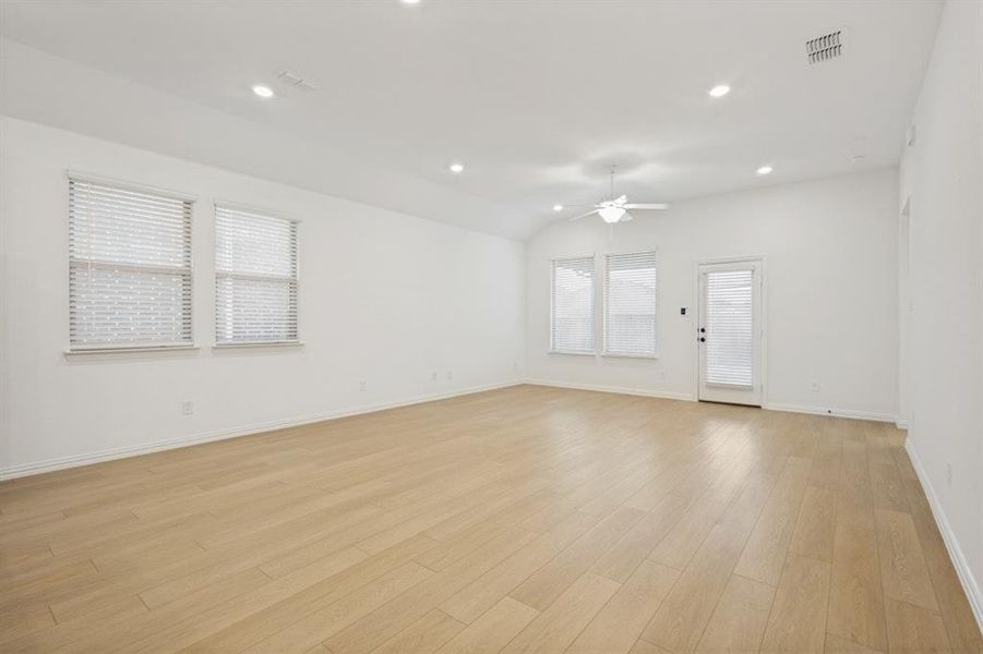 Spacious room featuring wood-finish flooring, vaulted ceiling, and recessed lighting