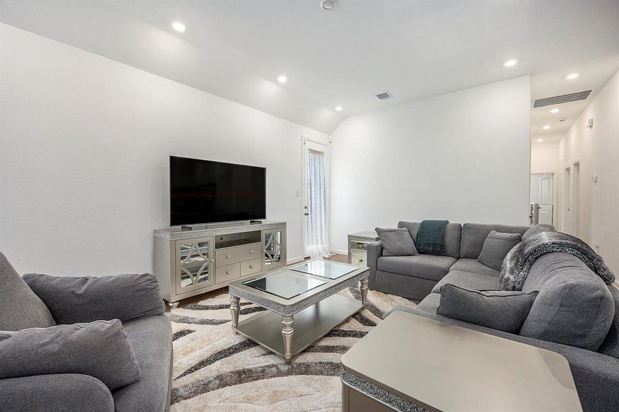 This modern living room features a spacious, light-filled living area. The open space and recessed lighting create a cozy, inviting atmosphere.