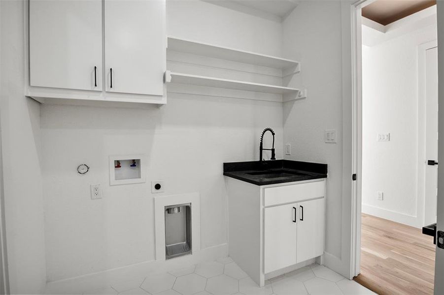 Washroom featuring sink, hookup for a washing machine, hookup for an electric dryer, cabinets, and light hardwood / wood-style floors