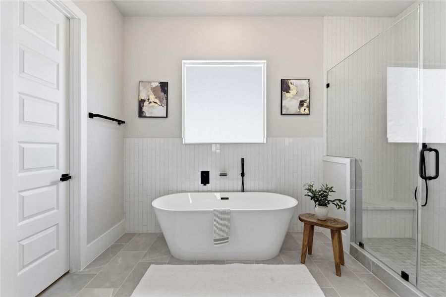 A freestanding soaking tub serves as a focal point, framed by natural light and clean vertical tile detailing. A freestanding soaking tub serves as a focal point, framed by natural light and clean vertical tile detailing.