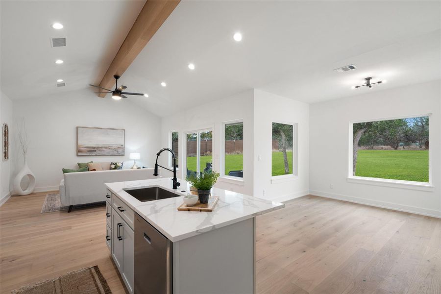 Living room with vaulted ceiling with beams, light hardwood / wood-style flooring, sink, and plenty of natural light