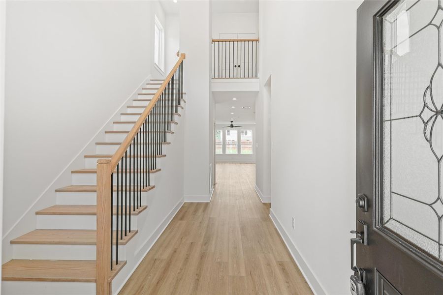 Stunning grand entry foyer featuring soaring ceilings and a beautiful staircase leading to the second floor. A bright and open welcome with elegant finishes and timeless design. To the right is the mudroom, just off the garage entry.