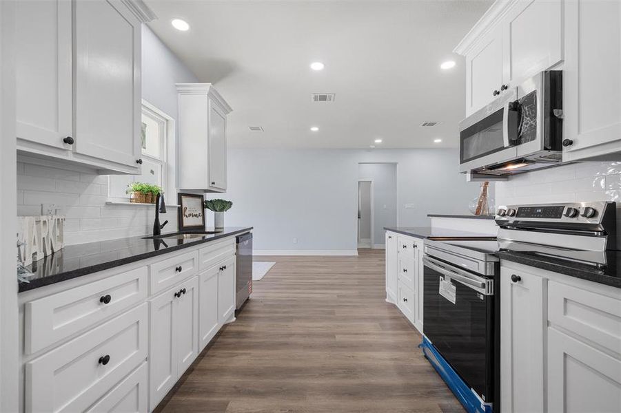 Kitchen with tasteful backsplash, stainless steel appliances, recessed lighting, and white cabinets