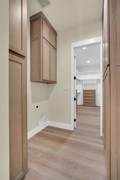 Laundry room with cabinets, hookup for an electric dryer, and light wood-type flooring