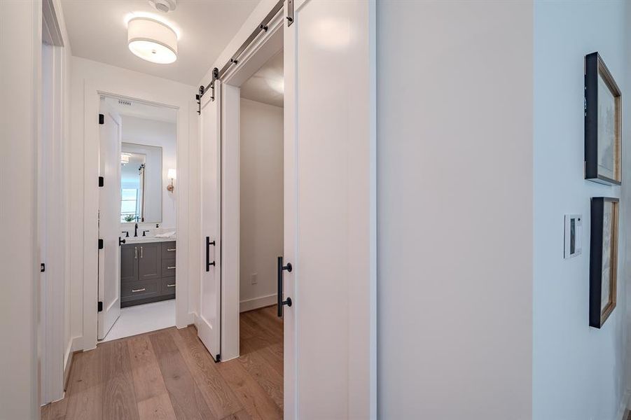 Corridor featuring light wood-type flooring and a barn door Corridor featuring light wood-type flooring and a barn door
