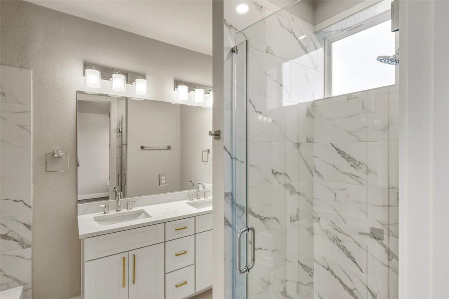 Discover luxury in this master bathroom featuring a double vanity with quartz countertops, elegant hardware, striking light fixtures, and a separate shower and tub for ultimate relaxation. Discover luxury in this master bathroom featuring a double vanity with quartz countertops, elegant hardware, striking light fixtures, and a separate shower and tub for ultimate relaxation.