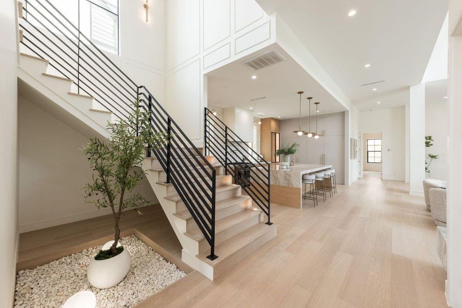 Designed as more than a passageway, this statement stairwell blends modern lines with organic serenity. Clean iron balusters rise alongside a curated pebble bed and layered greenery, creating an unexpected design feature that feels both grounded and artfully composed.