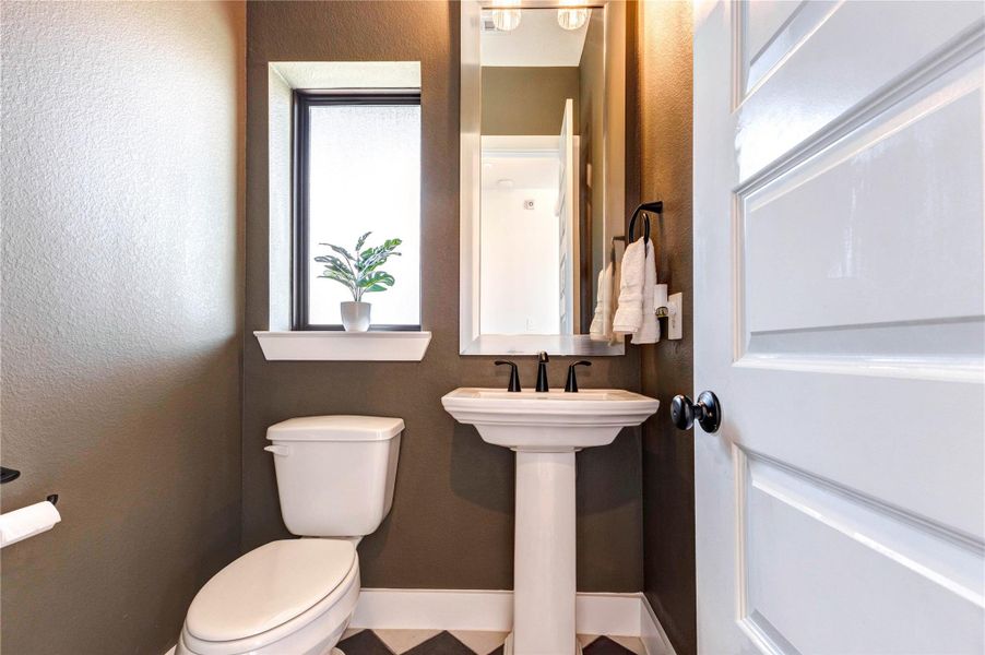 Powder room with stylish black-and-white checkered flooring, a matching washer and dryer, and green cabinetry with a sleek countertop. The room connects to a spacious walk-in closet. Powder room with stylish black-and-white checkered flooring, a matching washer and dryer, and green cabinetry with a sleek countertop. The room connects to a spacious walk-in closet.